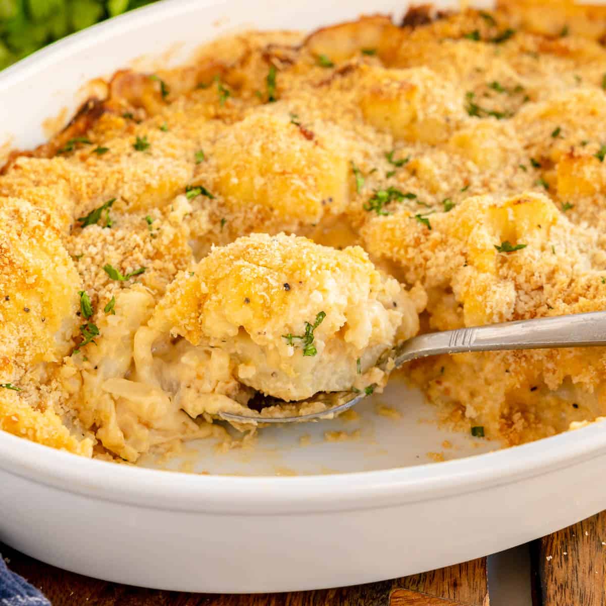 Cheesy cauliflower au gratin in a white dish with a spoon.