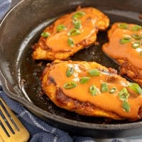 Chicken diablo s in a skillet with sauce and green onions.