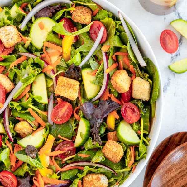 Garden salad with fresh vegetables and crunchy croutons, served in a clean white bowl.
