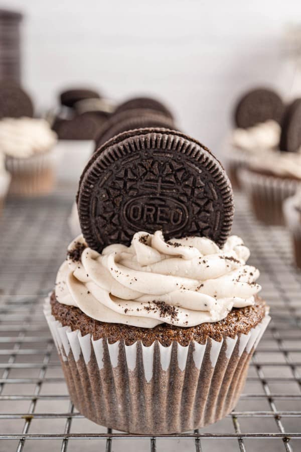 oreo cupcake with an oreo on top on a wire rack.