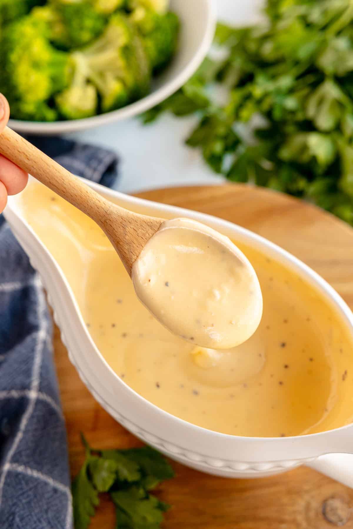 cheese sauce on a spoon with a gravy boat.