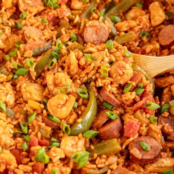 jambalaya in a skillet with a wooden spoon.