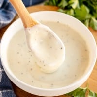 white sauce in a bowl with a wooden spoon.