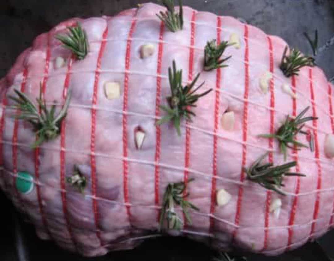 boneless leg of lamb with garlic and rosemary stuffed into cuts.