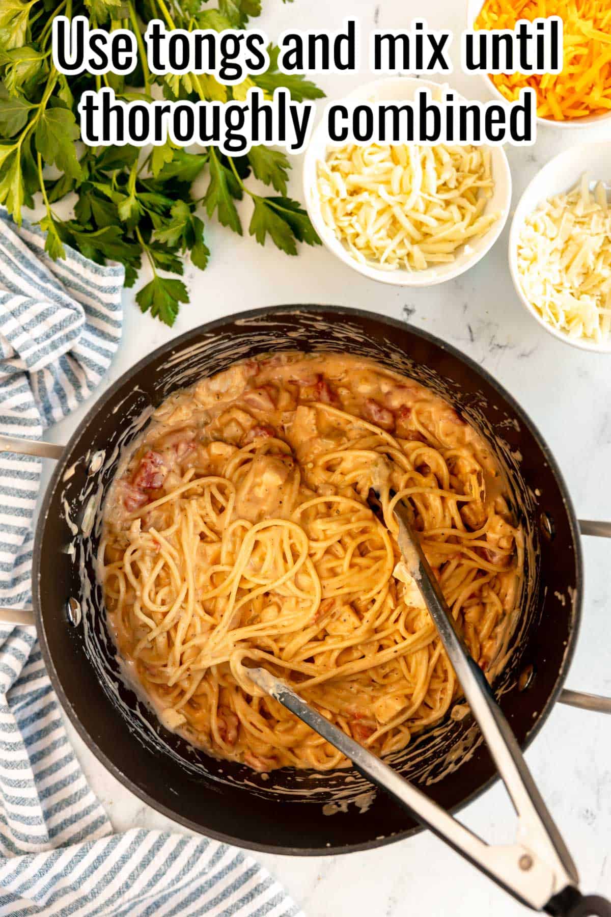 Use tongs to thoroughly combine creamy spaghetti and chicken.