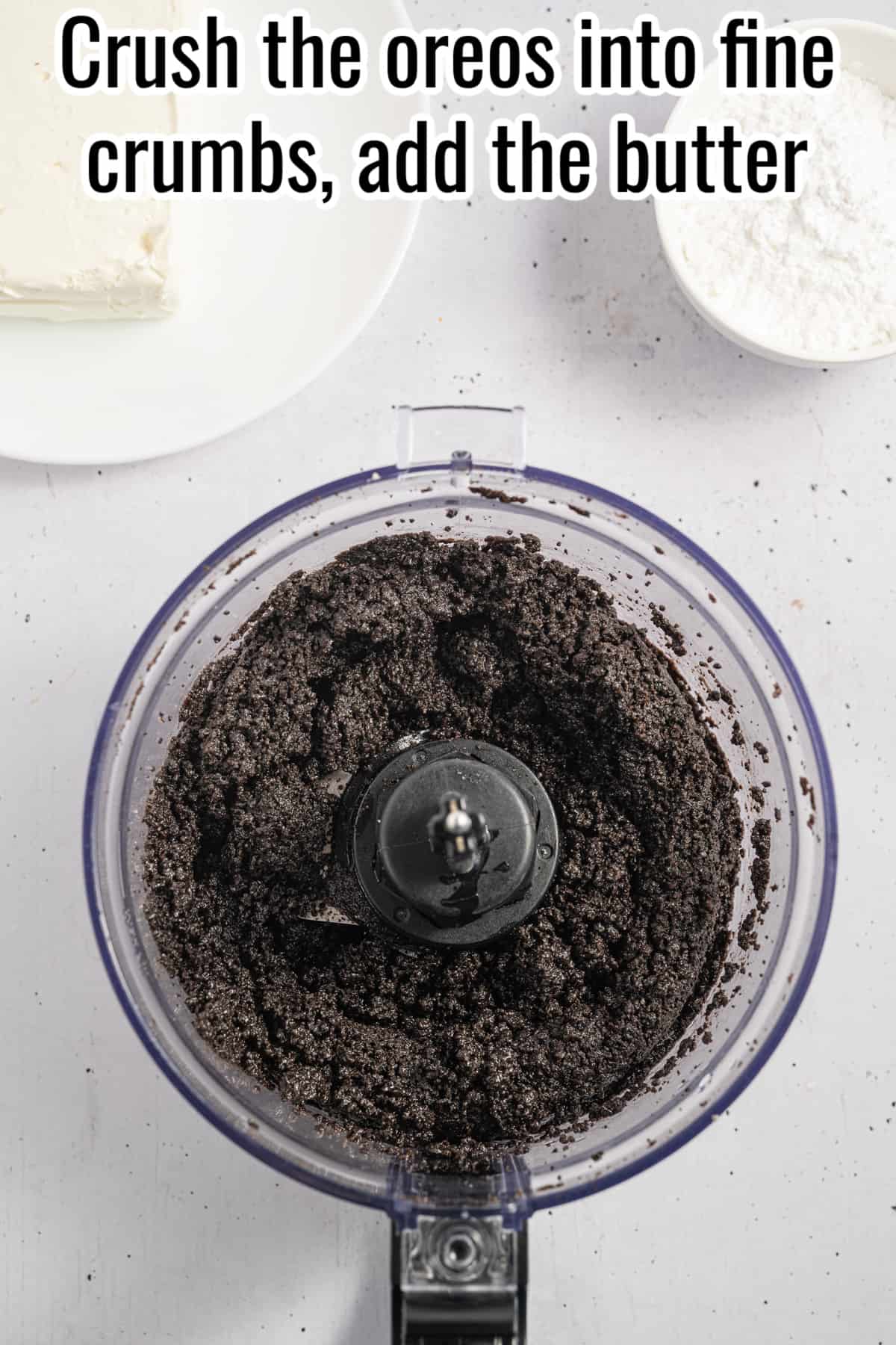 A blender with ground oreos and butter in it.