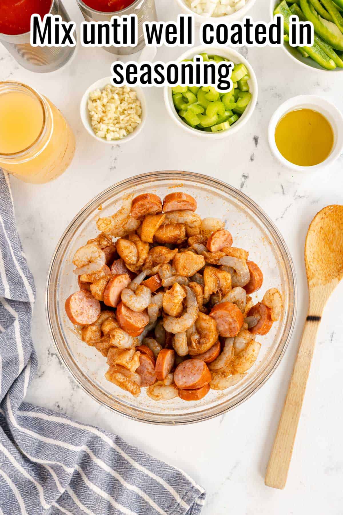 a glass bowl with seasoned chicken, shrimp and sausage.