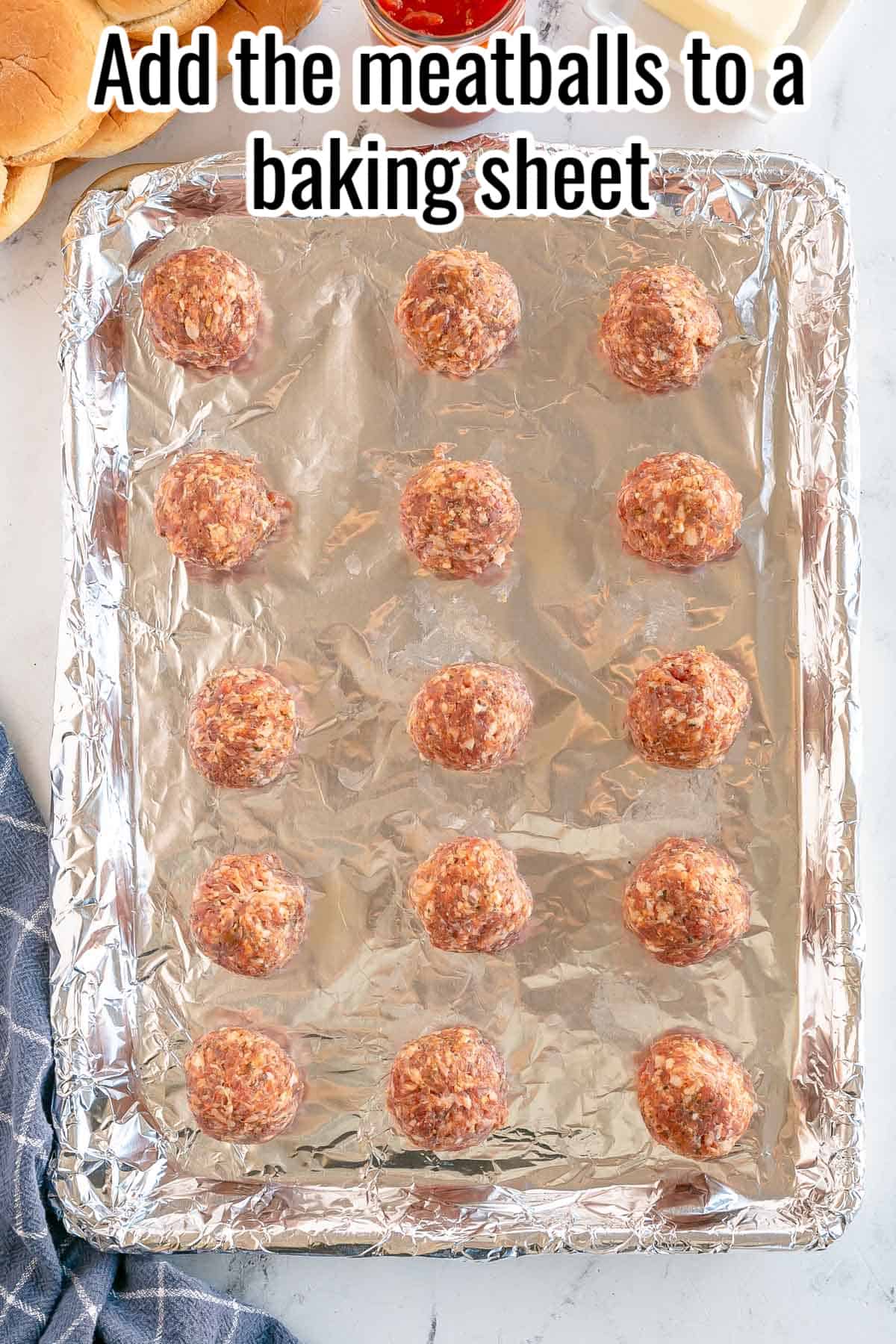 a baking sheet with raw meatballs.