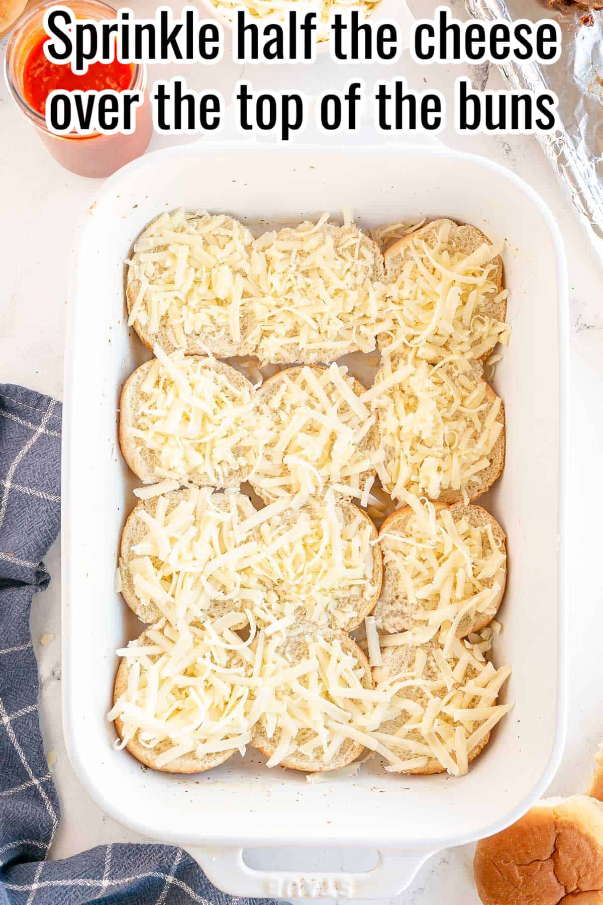 a white baking dish with slider bun bottoms, and cheese.