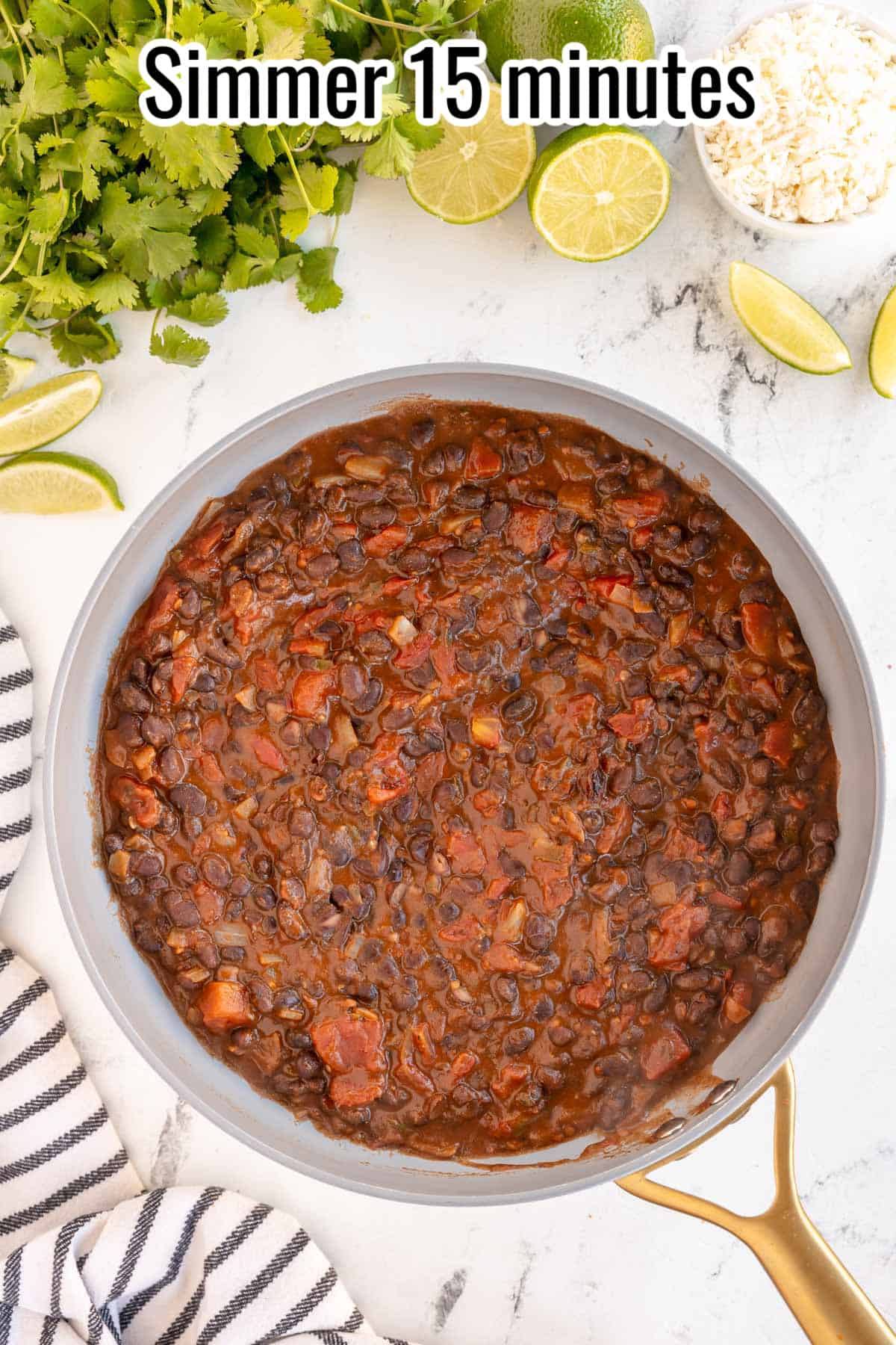 A skillet with black beans and lime next to it.
