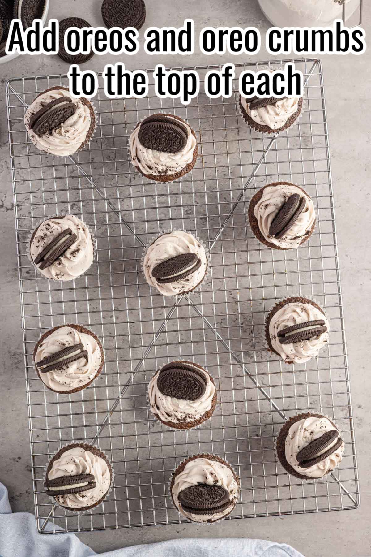 oreo cupcakes on a wire rack with words "add oreos and oreo crumbs to the top of each" overlaid in text.