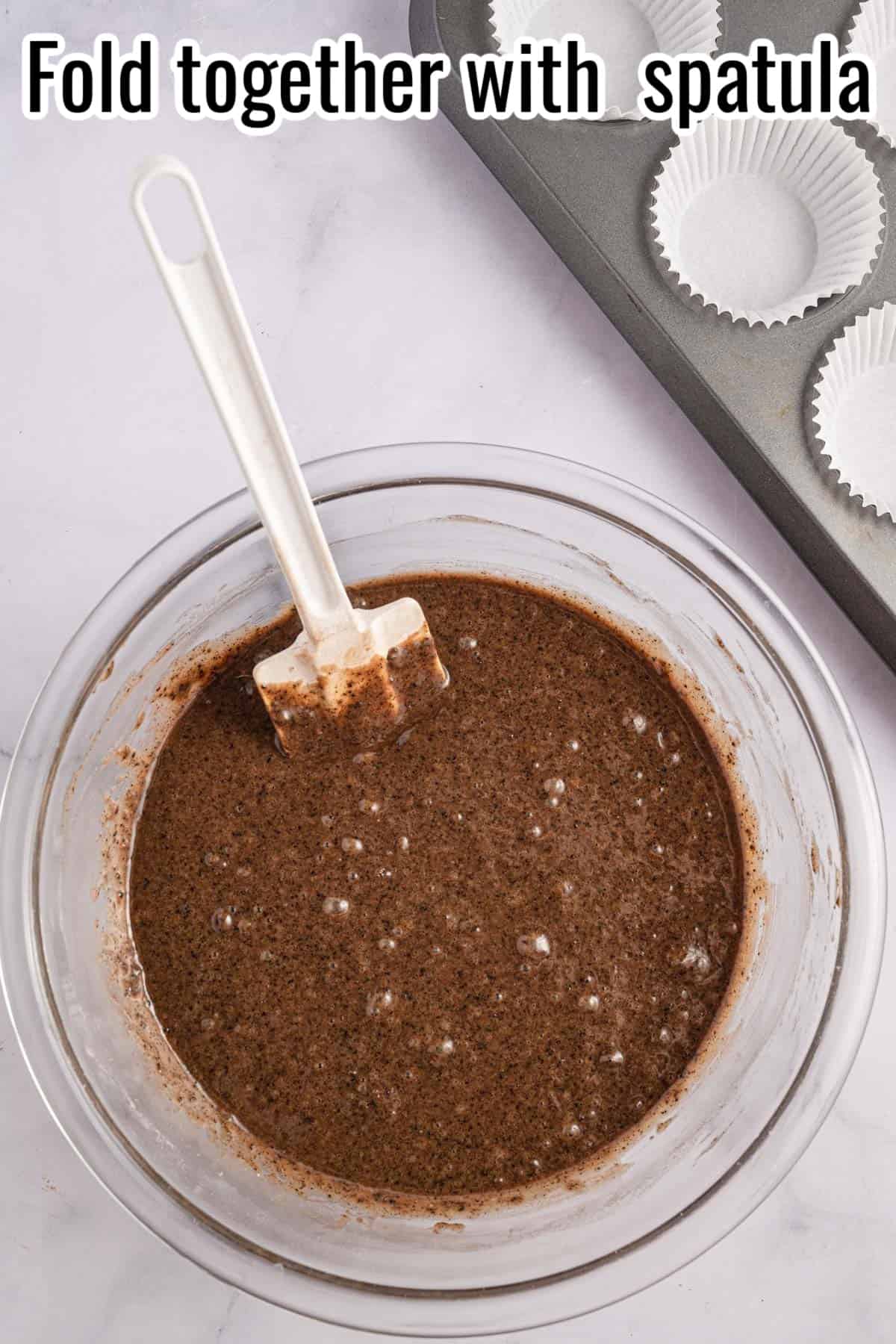A bowl of brownie batter with a spatula in it.