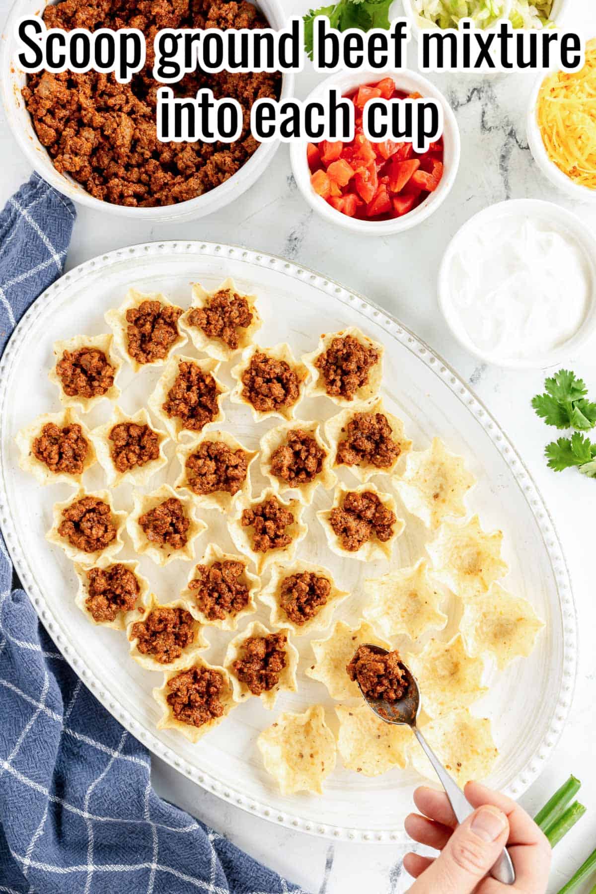 a hand scooping taco meat into mini taco bite shells.