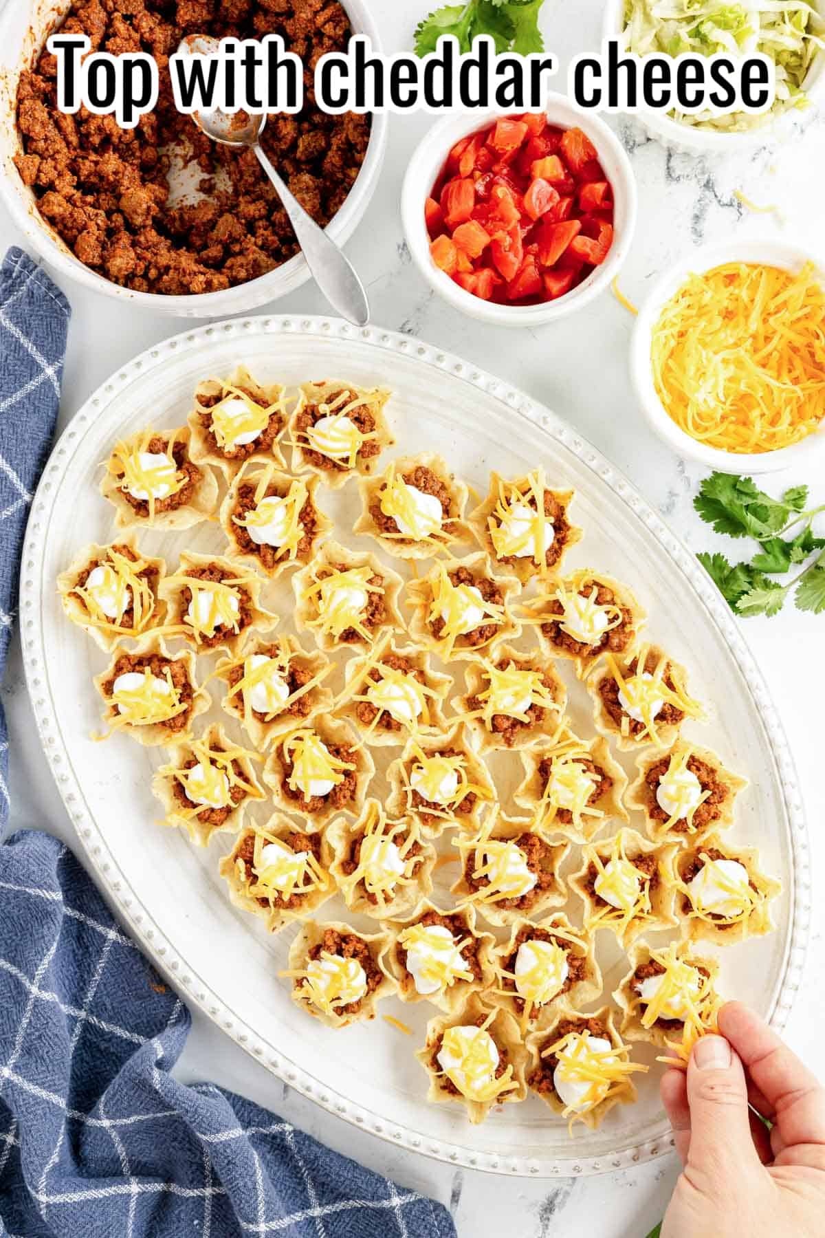 mini taco bites on a platter with cheese added.
