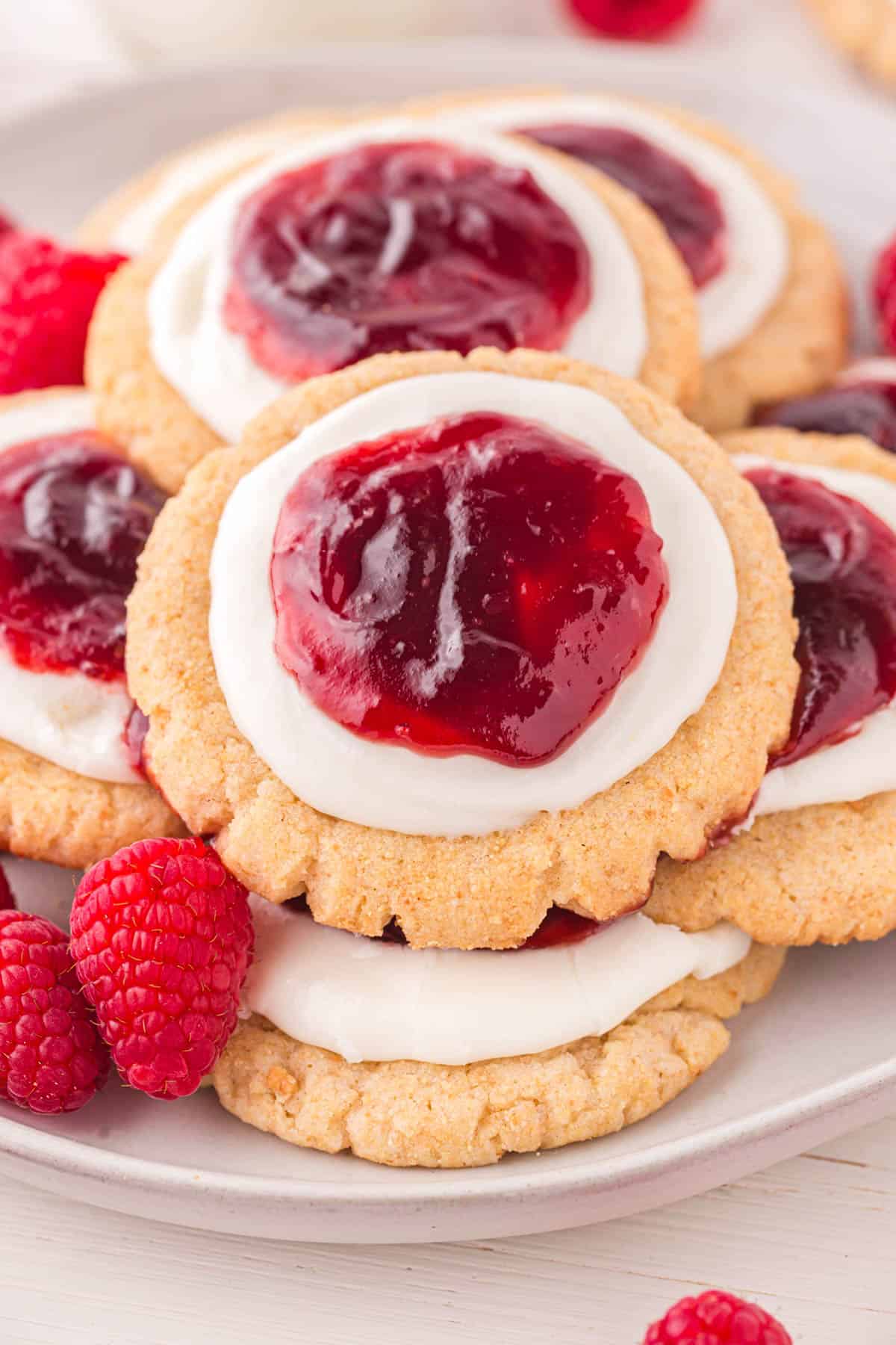 raspberry cheesecake cookies on a plate with raspberries.