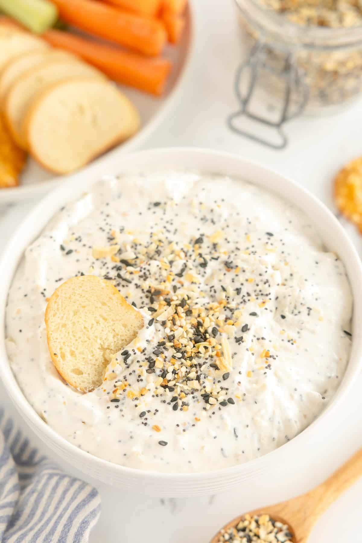 everything bagel dip with a spoon and extra seasoning over the top.