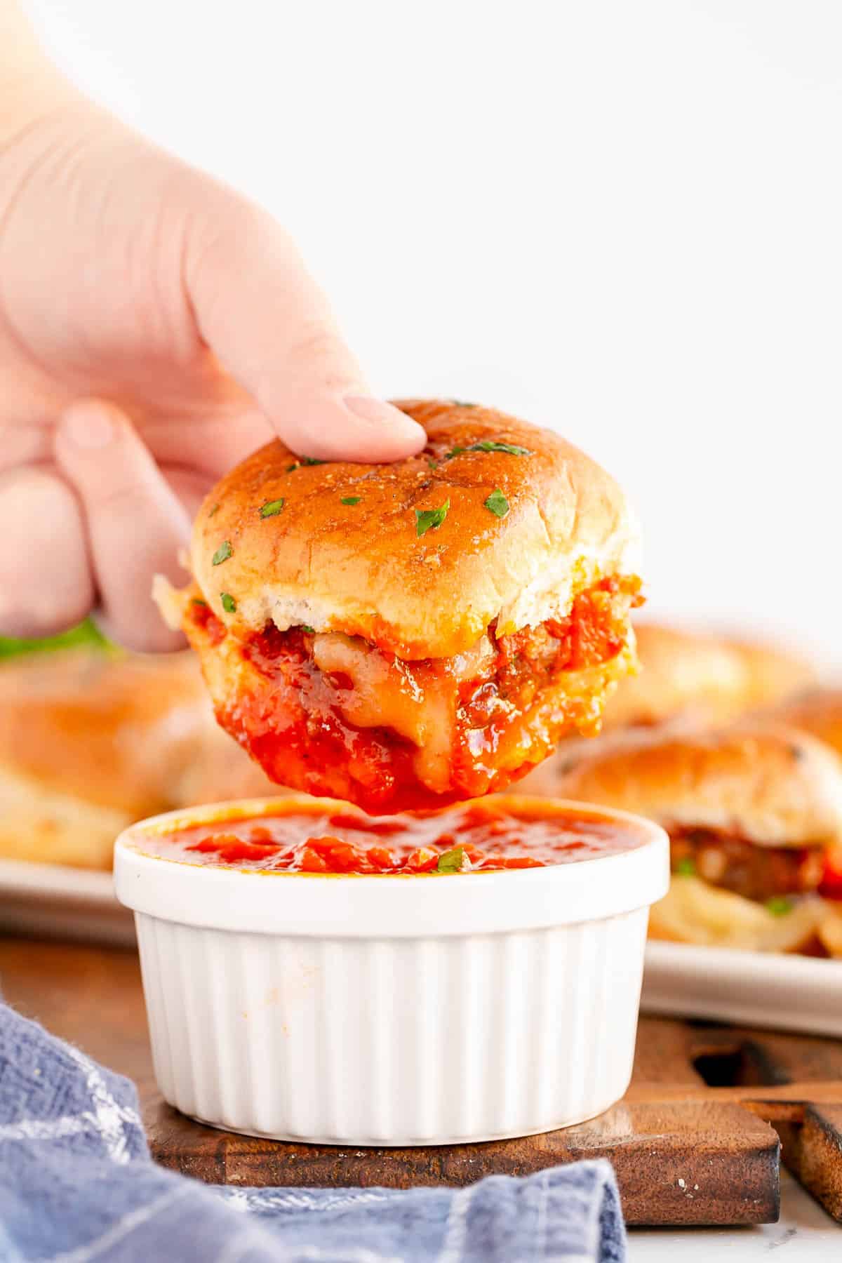 a meatball slider being dipped in marinara.