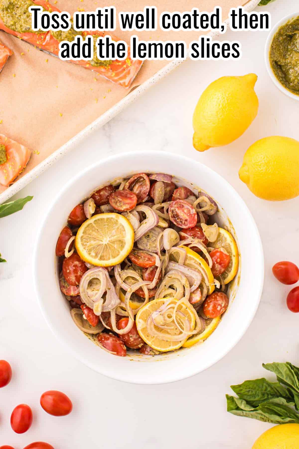 tomatoes, shallots and pesto in a bowl with lemon slices.