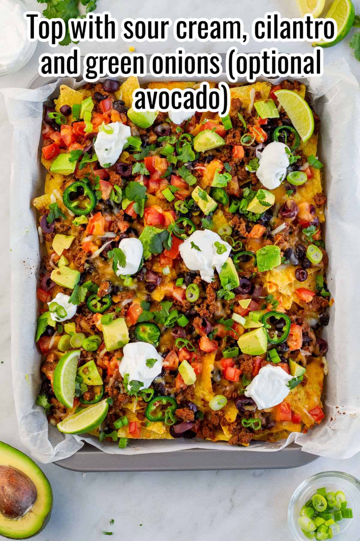 baked nachos with sour cream, onions and avocado added.