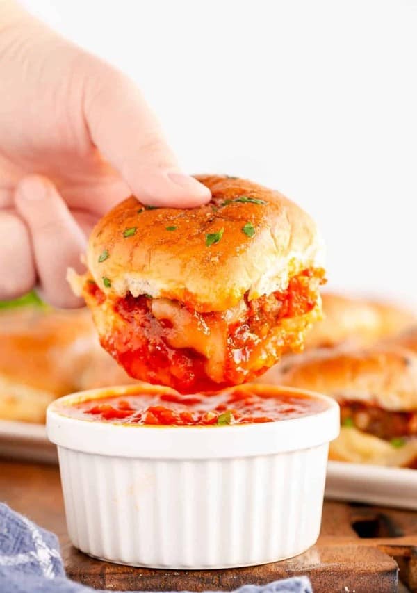 a meatball slider being dipped in marinara.