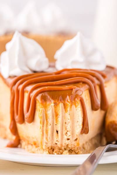 A slice of cheesecake drizzled with caramel sauce and topped with whipped cream.