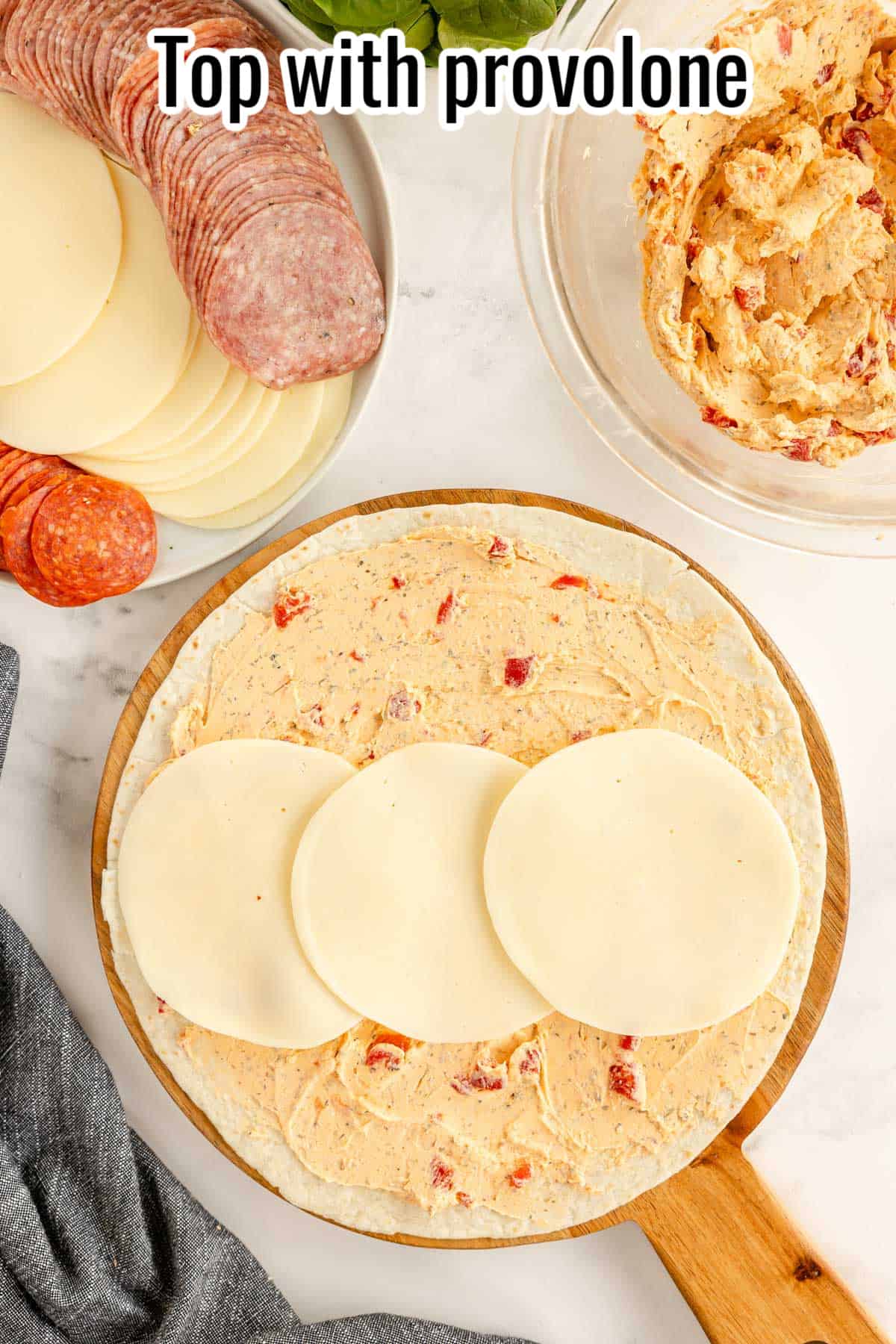 A tortilla spread with cream cheese mixture, and 3 slices of provolone.