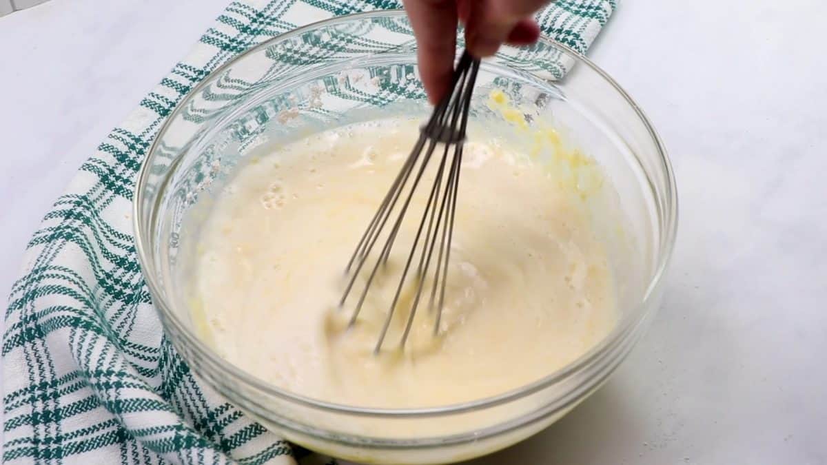 quiche batter being whisked in a glass bowl.