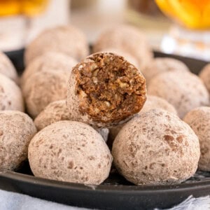 A bourbon ball with a bite taken out, showing the interior of pecans and cocoa.