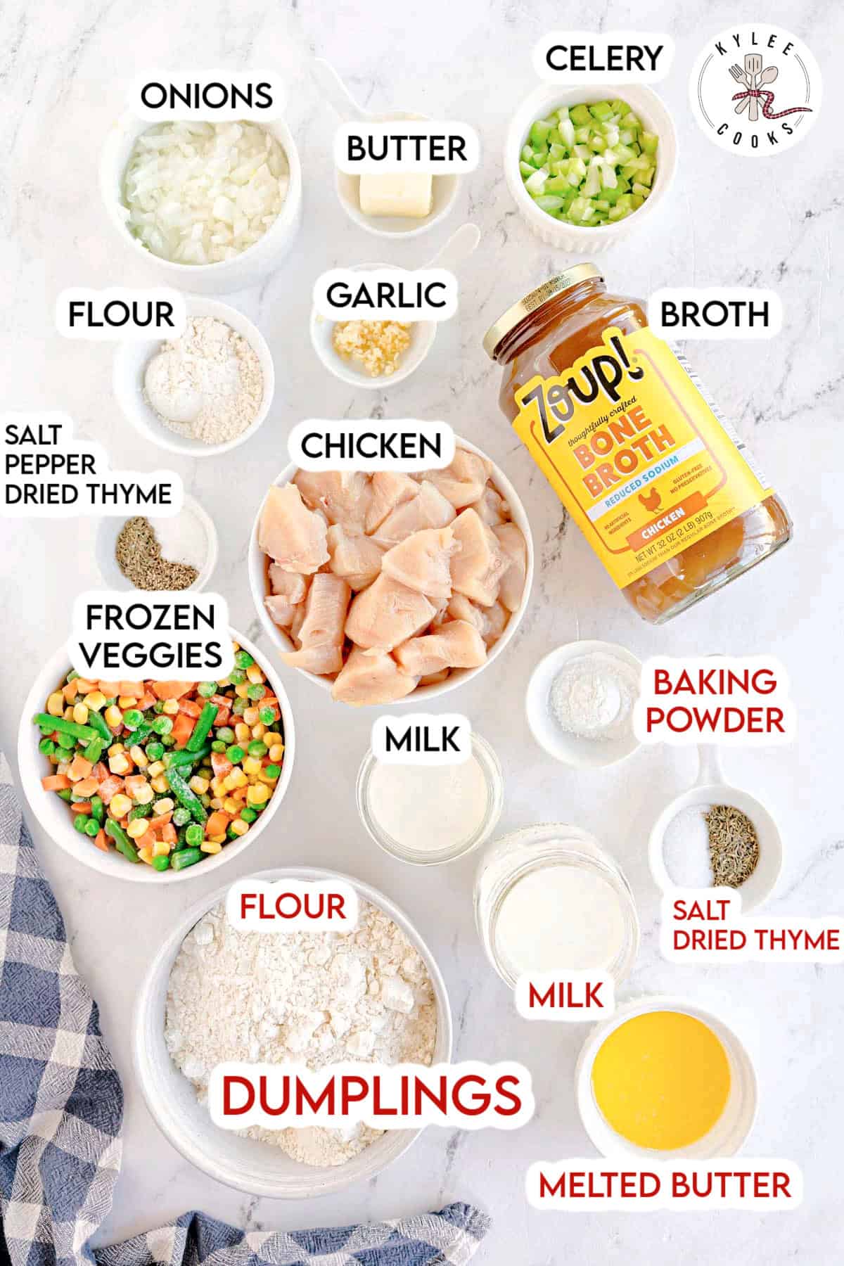 Ingredients for chicken and dumplings arranged on a white surface, including chopped chicken, vegetables, flour, and broth. Text on the image labels each item.