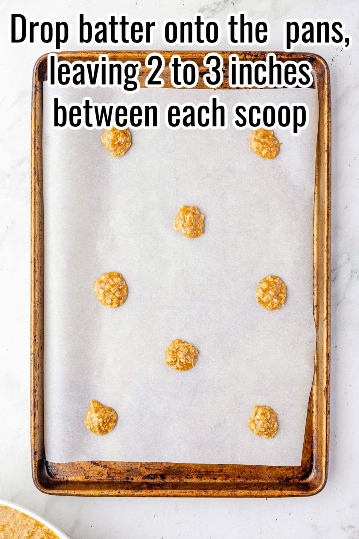 Scoops of batter spaced on a baking sheet. Text on the image says 'Drop batter onto the pans, leaving 2 to 3 inches between each scoop'.