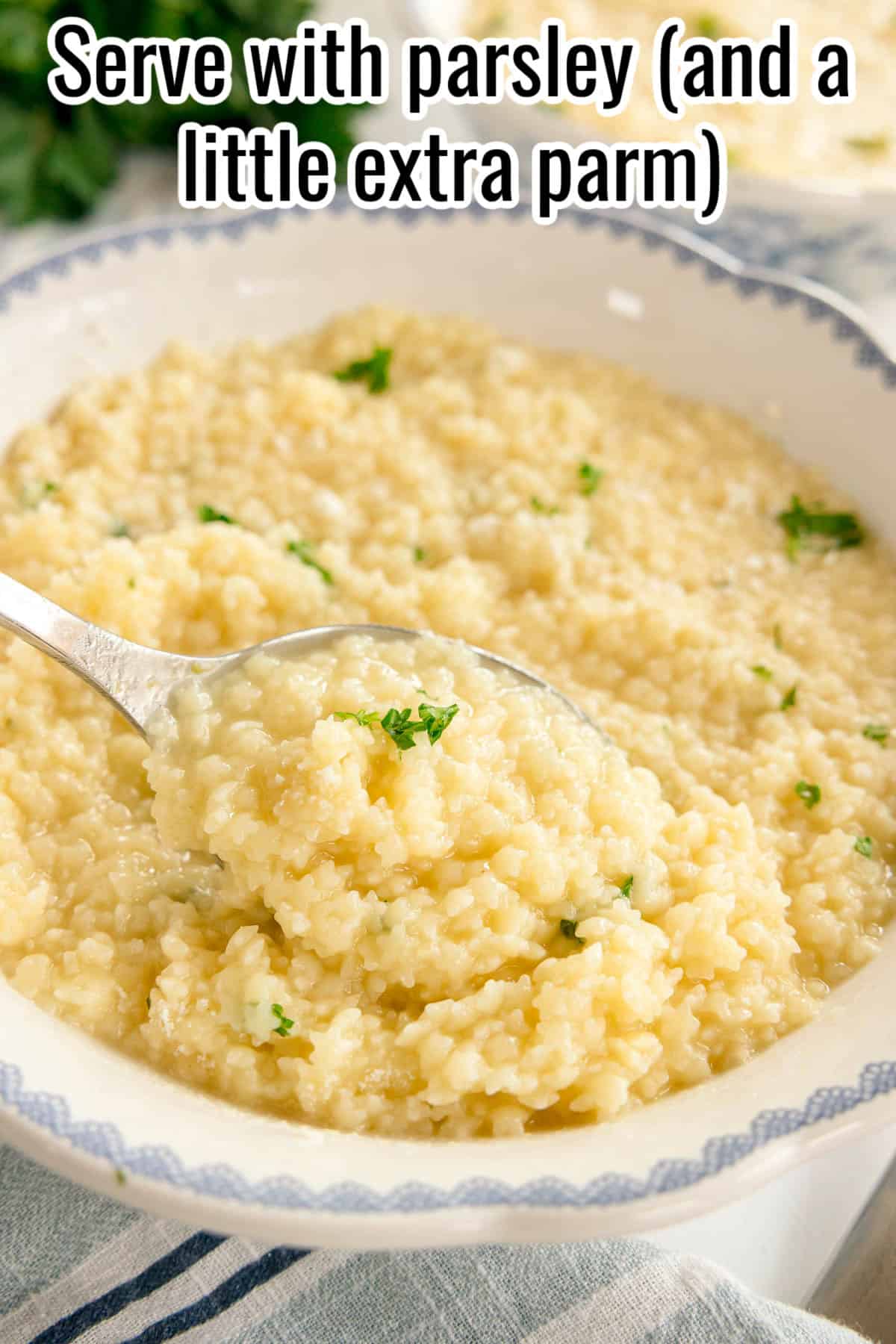 Spoonful of pastina above a bowl, garnished with parsley. Text on the image says 'Serve with parsley (and a little extra parm)'.