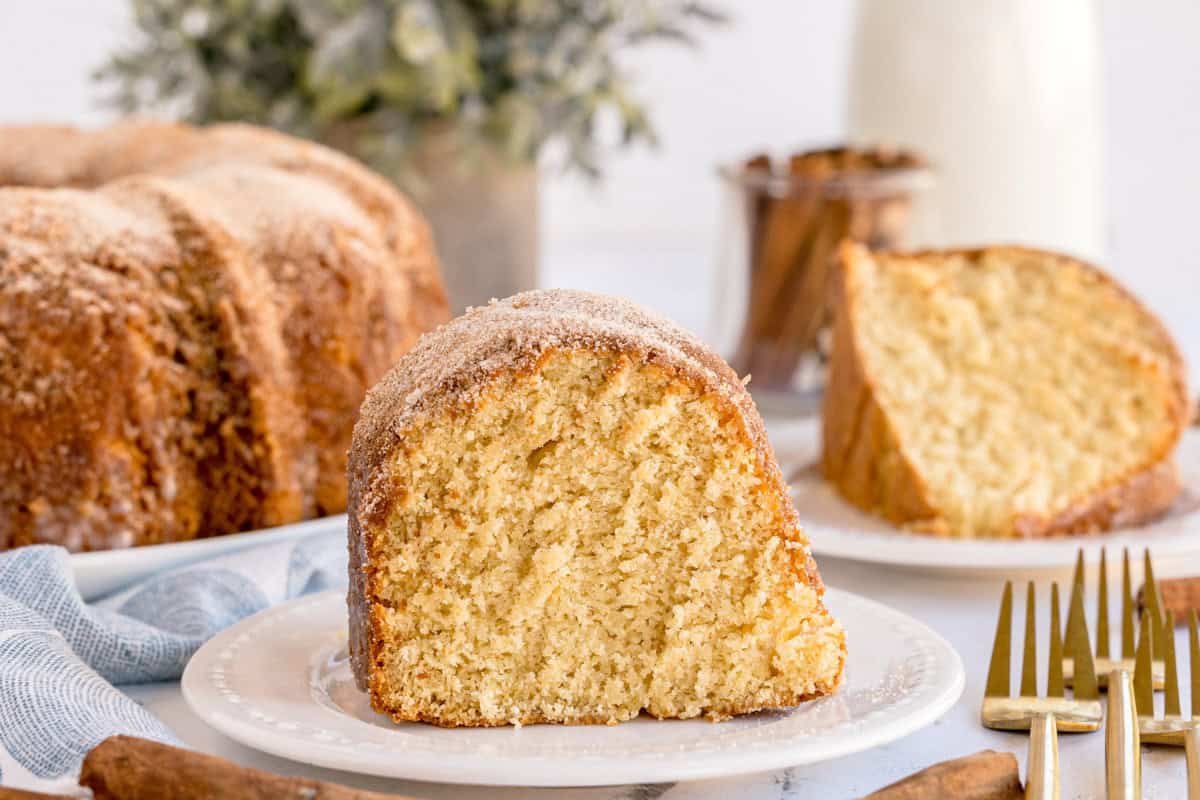 A slice of snickerdoodle bundt cake on a white plate with more slices in the background.