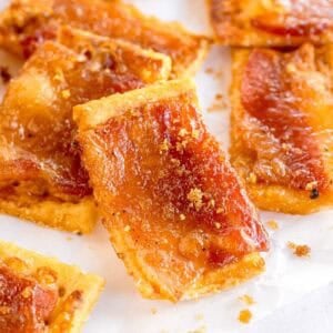 Close-up of bacon-topped crackers with brown sugar sprinkled on top.