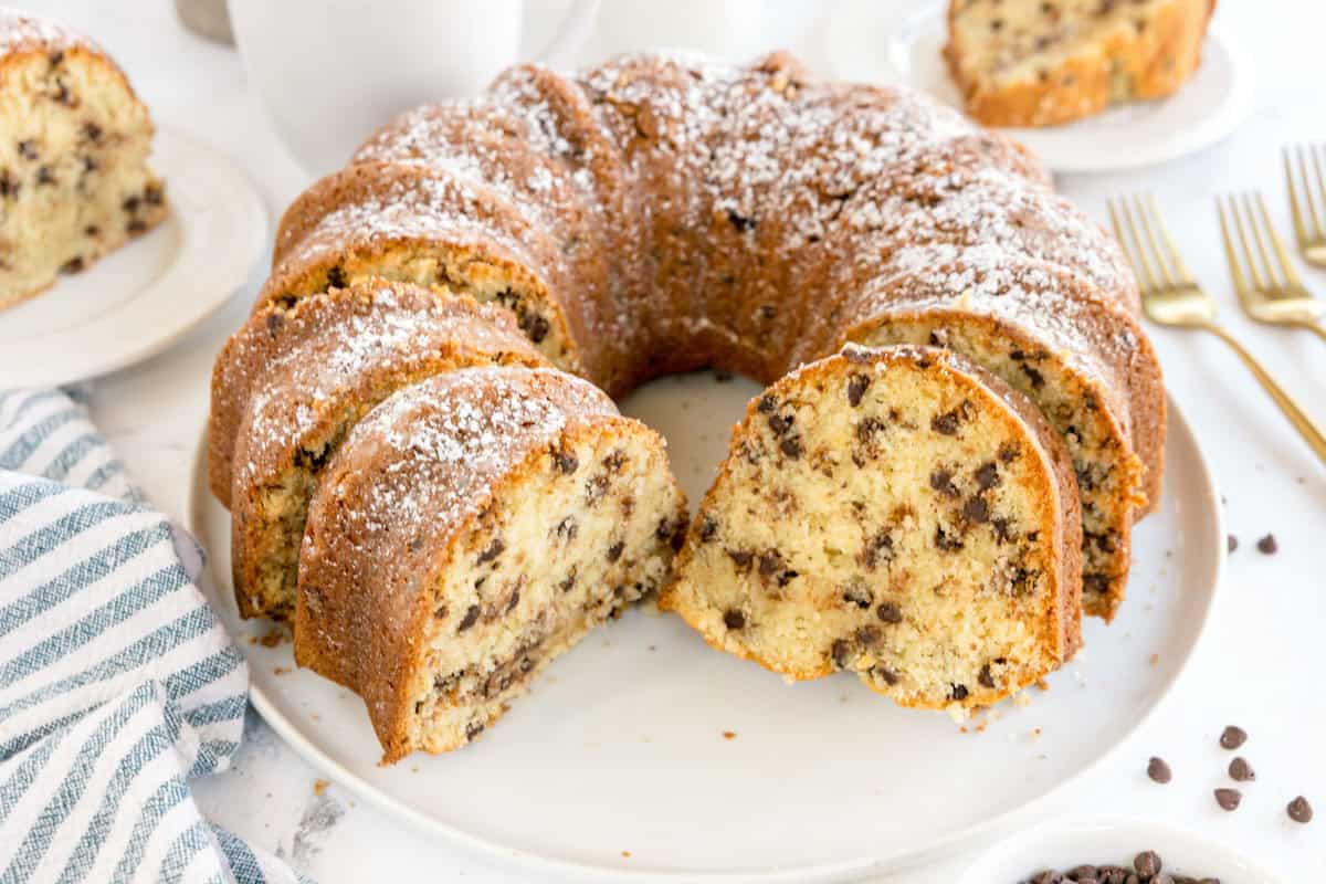 A chocolate chip bundt cake with several slices cut and served on a white plate.