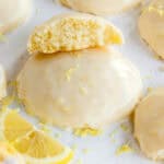 A cookie topped with glaze and lemon zest, with a half cookie resting on top.