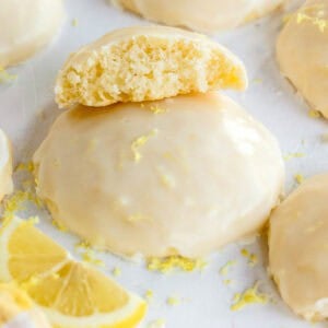 A cookie topped with glaze and lemon zest, with a half cookie resting on top.