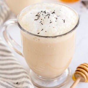 Close-up of a tea latte topped with foam and sprinkled tea leaves.