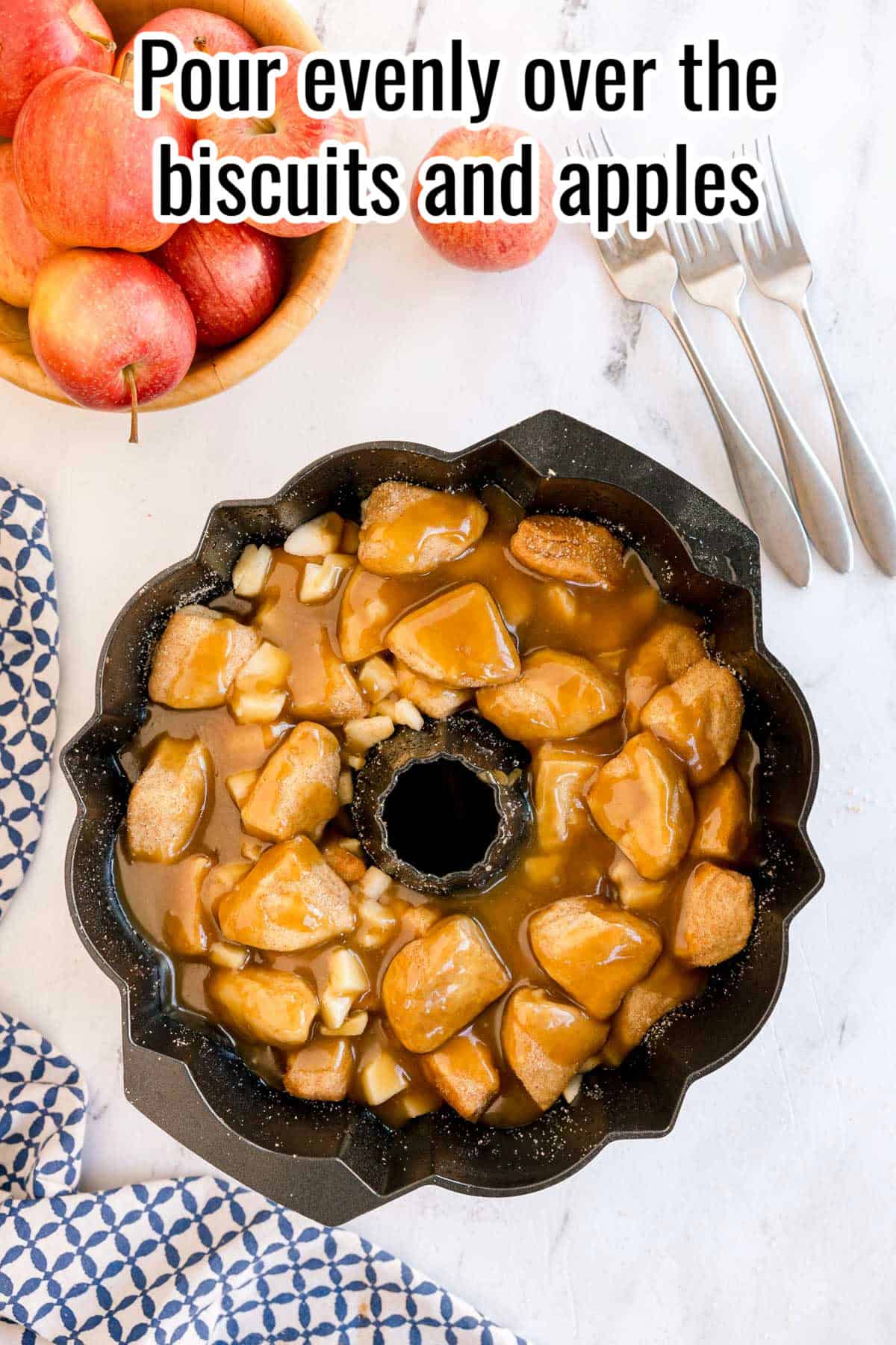 A bundt pan with biscuit pieces and apples covered in caramel sauce. Text on the image says 'Pour evenly over the biscuits and apples'.