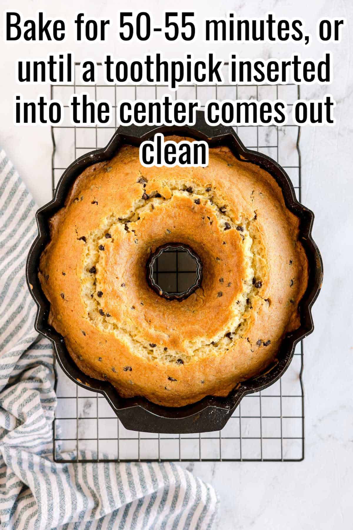 Baked bundt cake still in the pan on a wire rack. Text on the image says 'Bake for 50-55 minutes, or until a toothpick inserted into the center comes out clean'.