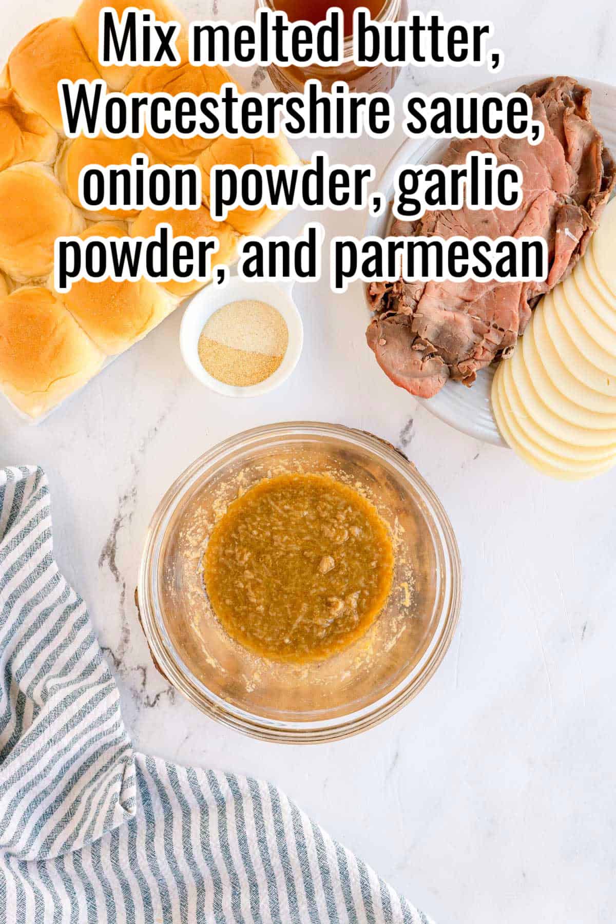Bowl of seasoned melted butter mixture on a counter with ingredients nearby. Text on the image says 'Mix melted butter, Worcestershire sauce, onion powder, garlic powder, and parmesan'.