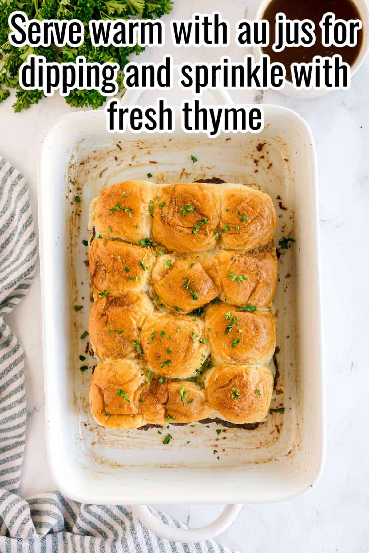 Baked sliders in a white dish topped with parsley. Text on the image says 'Serve warm with au jus for dipping and sprinkle with fresh thyme'.