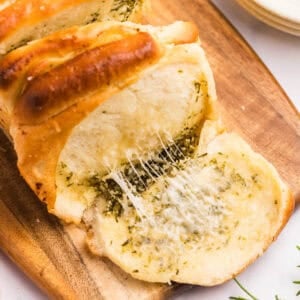 A slice of cheesy bread being pulled away, showing melted herbs and cheese.