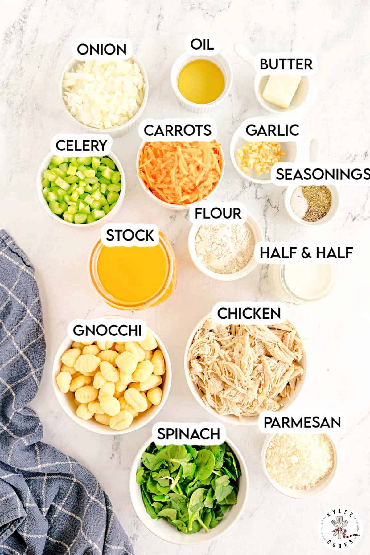 Small bowls with chopped onion, celery, shredded carrots, garlic, flour, seasonings, chicken stock, half and half, gnocchi, shredded chicken, spinach, and parmesan. Text on the image says 'ONION, CELERY, CARROTS, GARLIC, FLOUR, STOCK, OIL, BUTTER, SEASONINGS, HALF & HALF, GNOCCHI, CHICKEN, PARMESAN, SPINACH'.