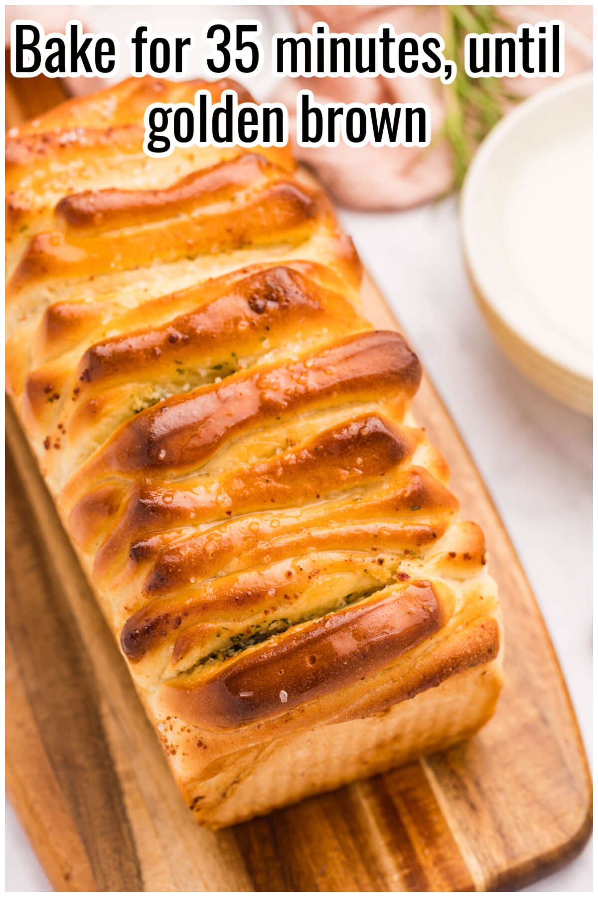 Baked cheesy pull-apart bread loaf with golden brown tops. Text on the image says 'Bake for 35 minutes, until golden brown'.