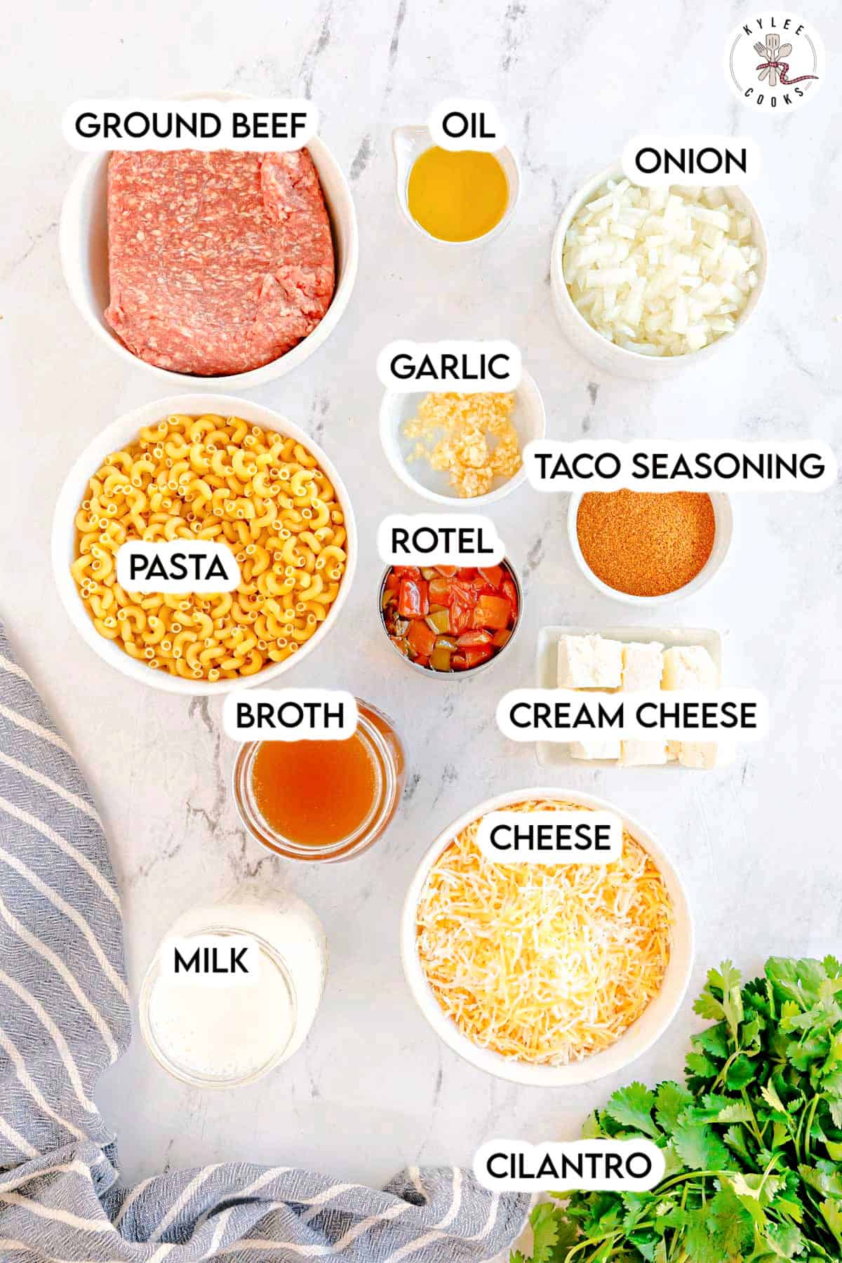 Ingredients in bowls including pasta, ground beef, broth, cheese, and spices. Text on the image says 'GROUND BEEF', 'OIL', 'ONION', 'GARLIC', 'TACO SEASONING', 'ROTEL', 'CREAM CHEESE', 'CHEESE', 'MILK', 'BROTH', 'PASTA', 'CILANTRO'.
