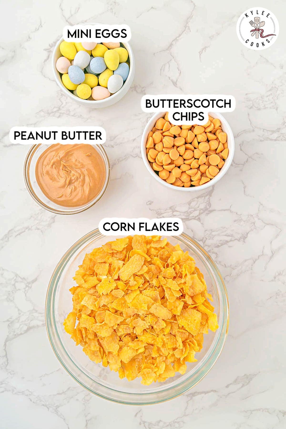 Bowls of mini eggs, butterscotch chips, peanut butter, and corn flakes. Text on the image says 'MINI EGGS BUTTERSCOTCH CHIPS PEANUT BUTTER CORN FLAKES'.