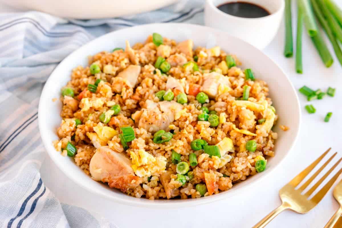 Bowl of chicken fried rice with peas, carrots, eggs, and green onions.