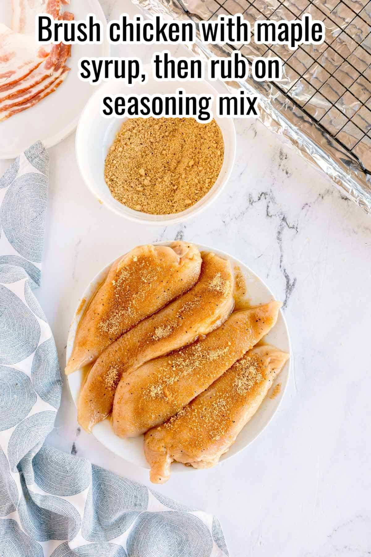 Chicken breasts coated with seasoning on a plate. Text on the image says 'Brush chicken with maple syrup, then rub on seasoning mix'.