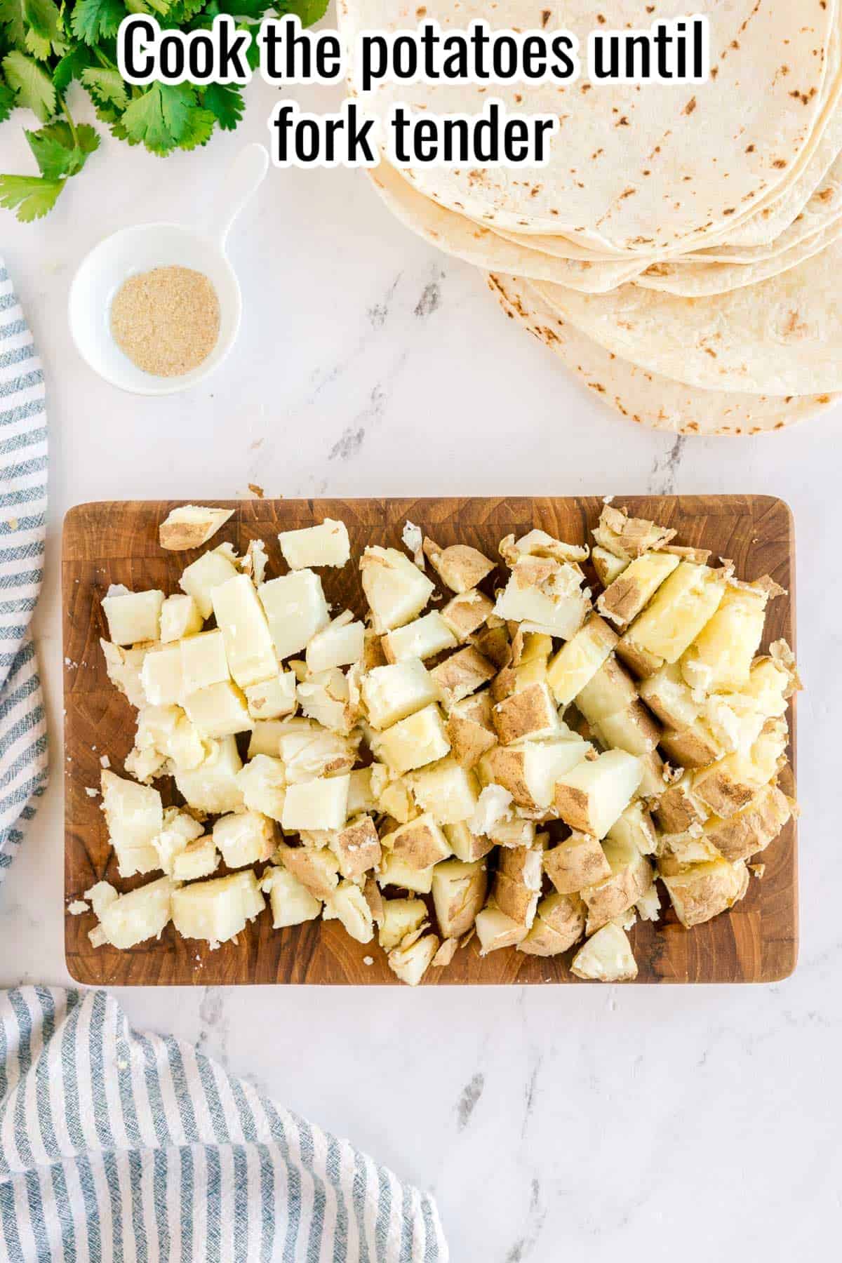 Chopped cooked potatoes on a cutting board with text overlay “Cook the potatoes until fork tender.”