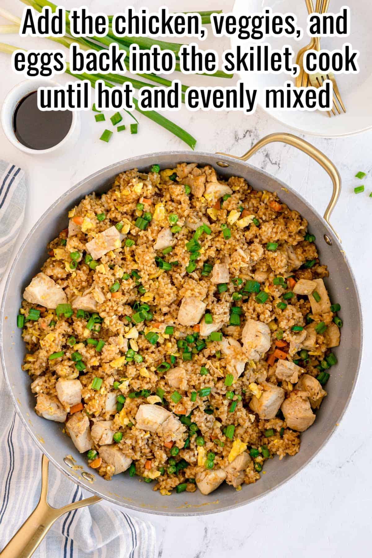 Chicken fried rice with chicken, peas, carrots, eggs, and green onions in a skillet. Text on the image says 'Add the chicken, veggies, and eggs back into the skillet, cook until hot and evenly mixed'.